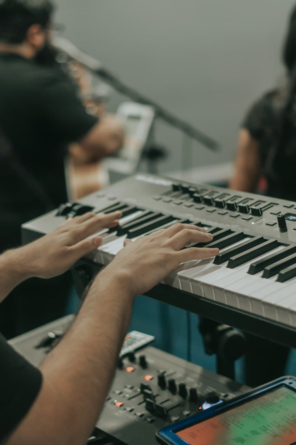 Fingrar som spelar ett digitalt piano med kontrollknappar.