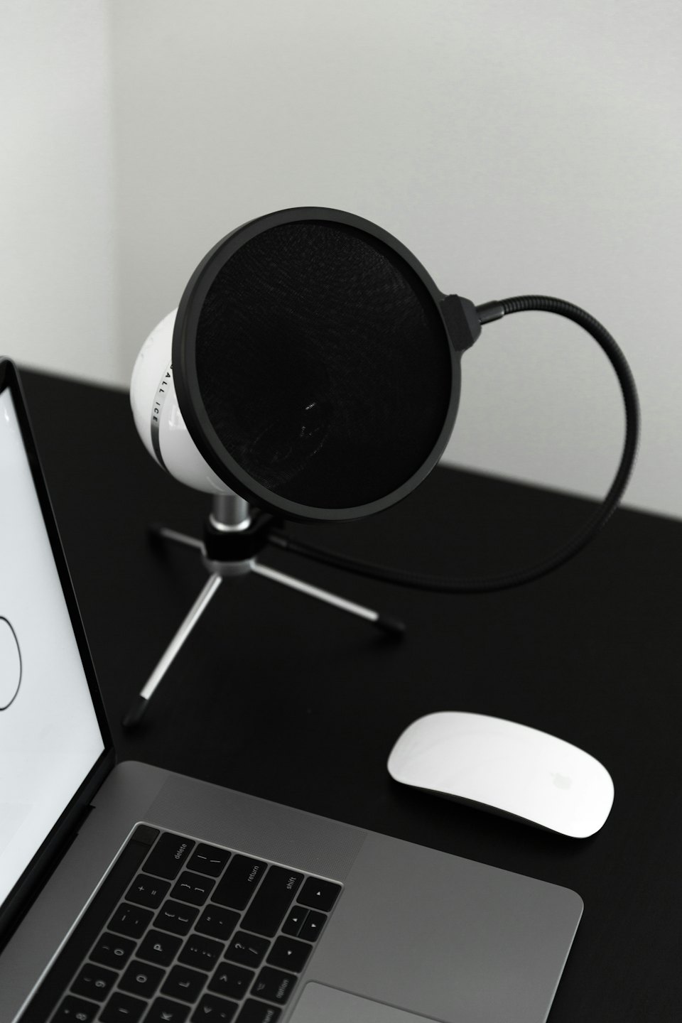 Bordsmikrofon och laptop på ett minimalistiskt skrivbord.
