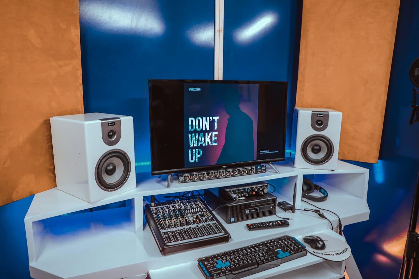 Modern ljudproduktionsarbetsplats med monitor, studiomonitorer och mixer.