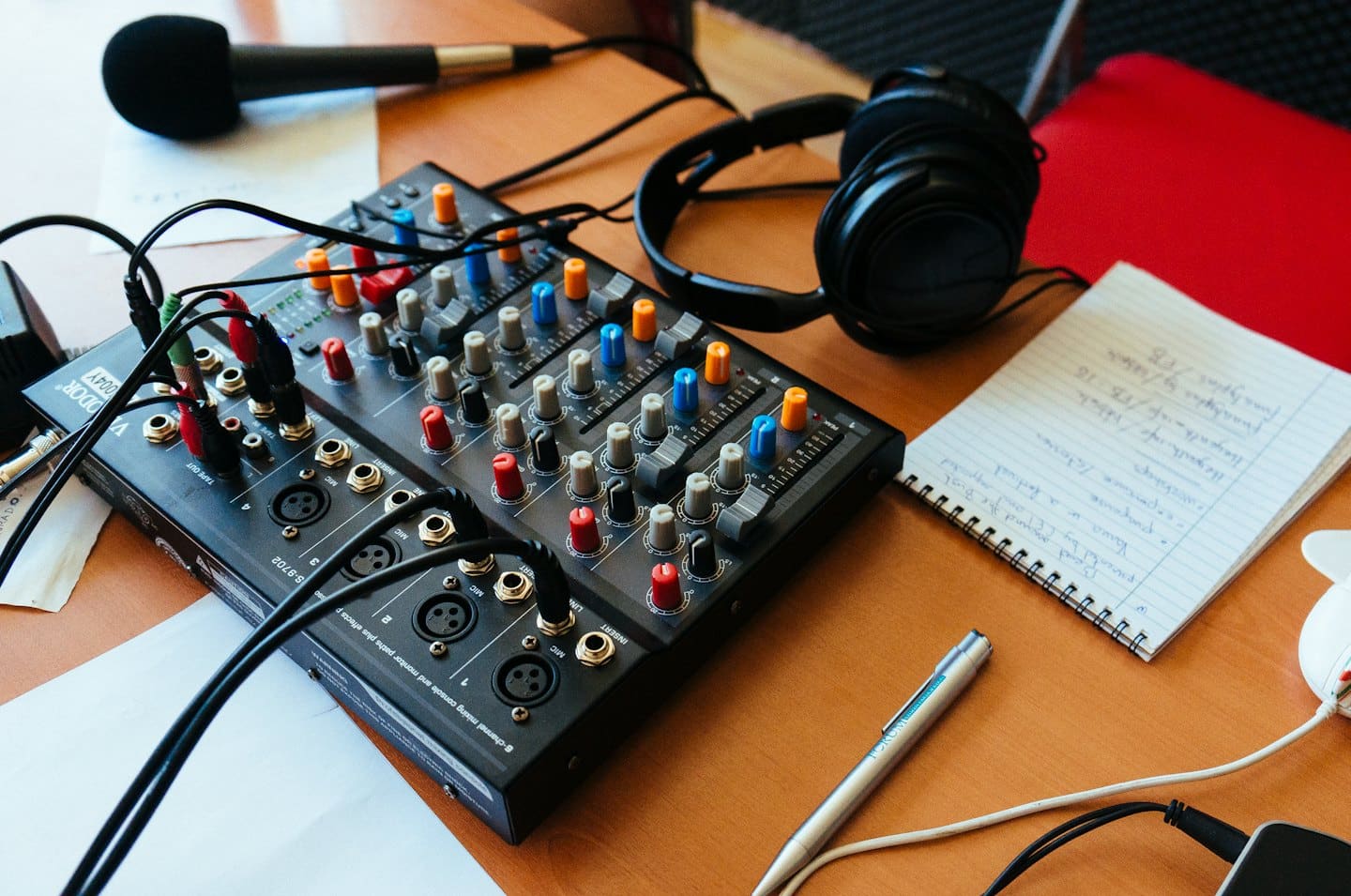 Ljudinspelningsutrustning på ett träskrivbord med mixerbord och hörlurar.
